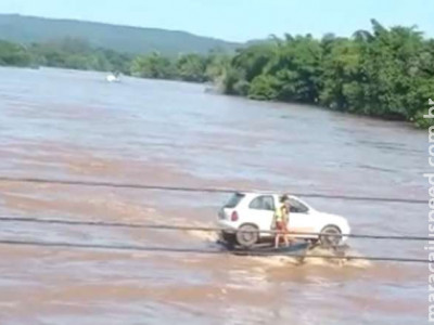 Carro é transportado por dois barcos no rio Taquari em Coxim