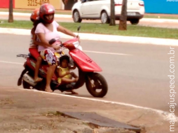 Menina é transportada entre as pernas de motociclista Menina é transportada entre as pernas de motociclista