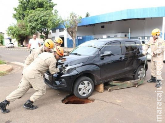 Asfalto cede e motorista de aplicativo tem carro preso em buraco