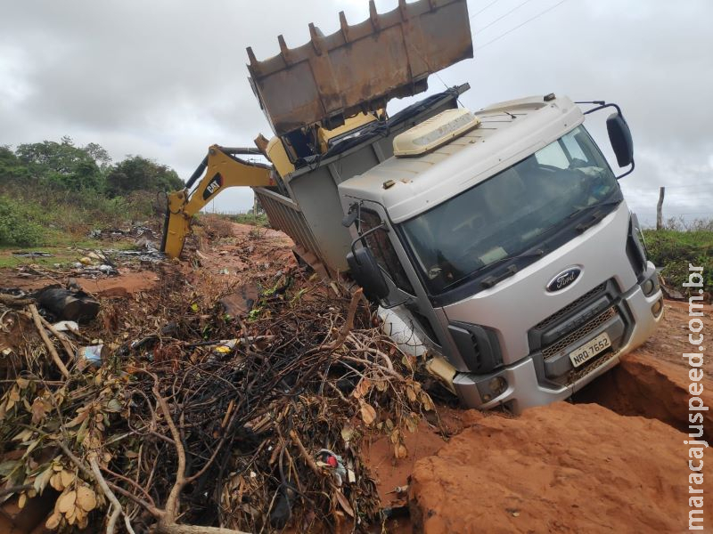 Caminhão que transportava retroescavadeira cai em buraco na Rua Acogo, em Anastácio