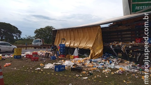 Carreta carregada de cerveja invade guard rail, lona estoura e carga é saqueada