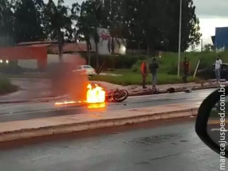 No meio de avenida, moto caída no asfalto pega fogo
