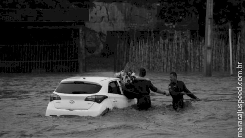 PMs salvam mãe e filho prestes a cair em córrego durante enchente PMs salvam mãe e filho prestes a cair em córrego durante enchente