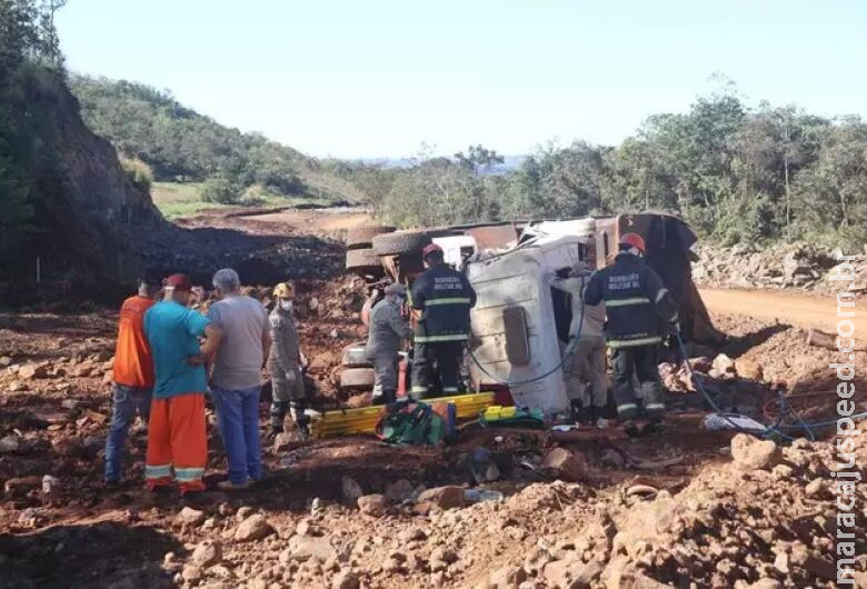 Caminhão com pedras tomba e motorista fica preso nas ferragens Caminhão com pedras tomba e motorista fica preso nas ferragens