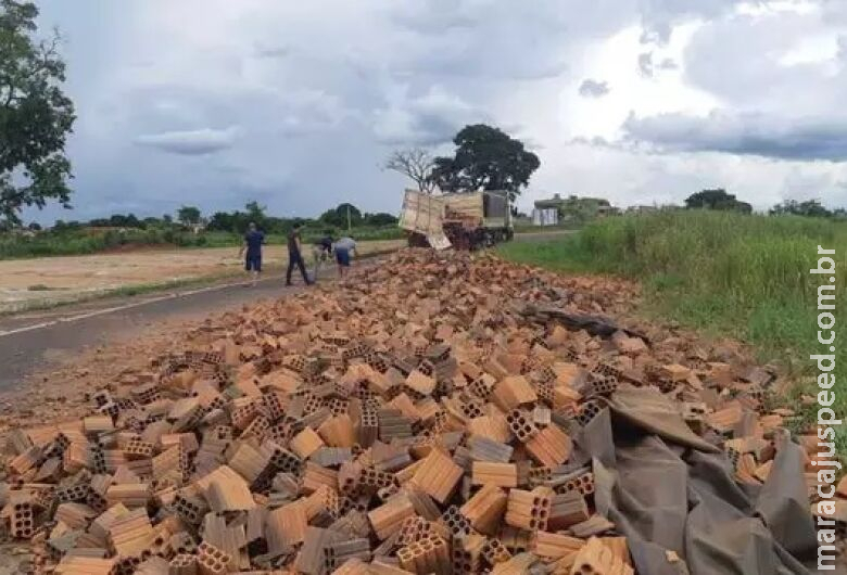 Carroceria de carreta abre e carga de tijolos fica espalhada em rodovia
